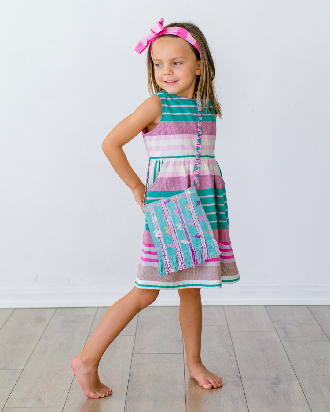 Todler girl wearing a green striped cotton, handmade dress and handbag