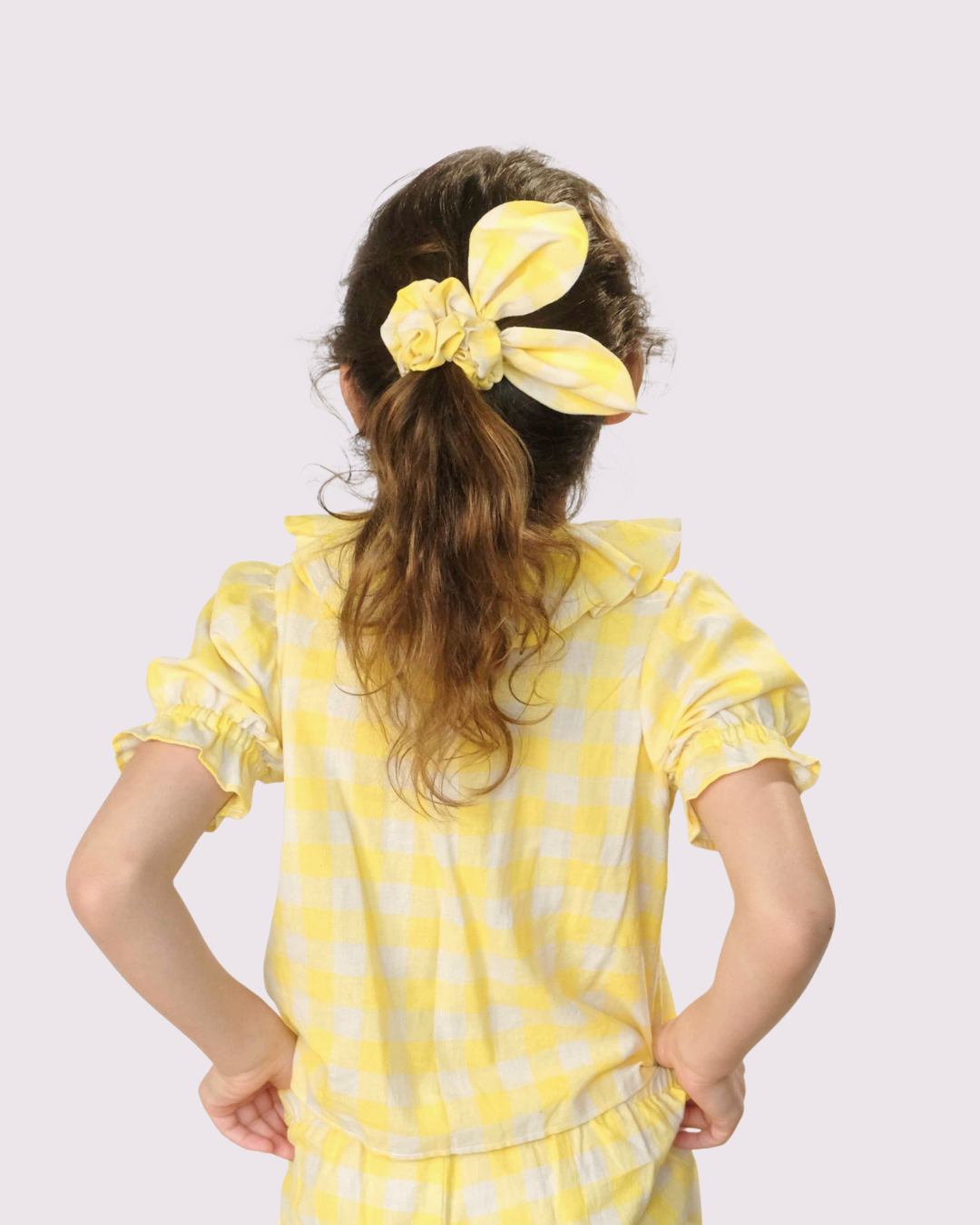 Girl wearing a gingham yellow scrunchy and top and bottom set